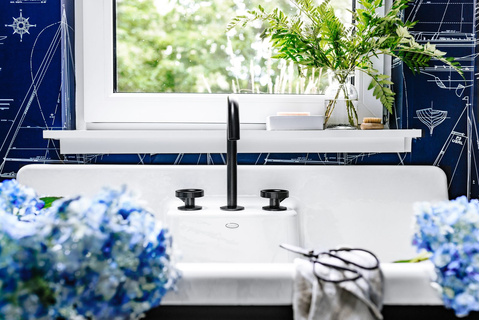 Close-up detail vignette of a powder-room faucet and stone basin — the kind of tight composition that fuels a designer's Instagram rotation and breaks up the rhythm of a project page.