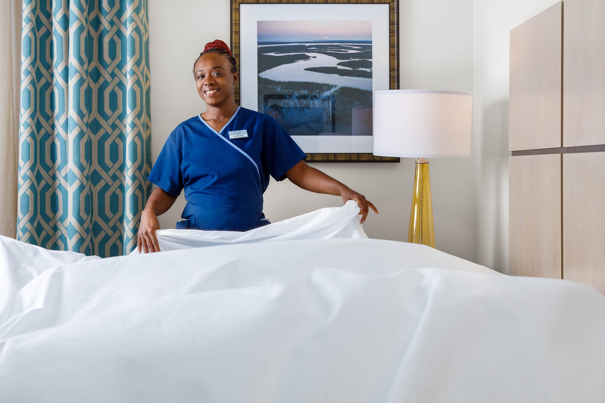 Hotel housekeeping staff making bed in guest room — hospitality lifestyle photography