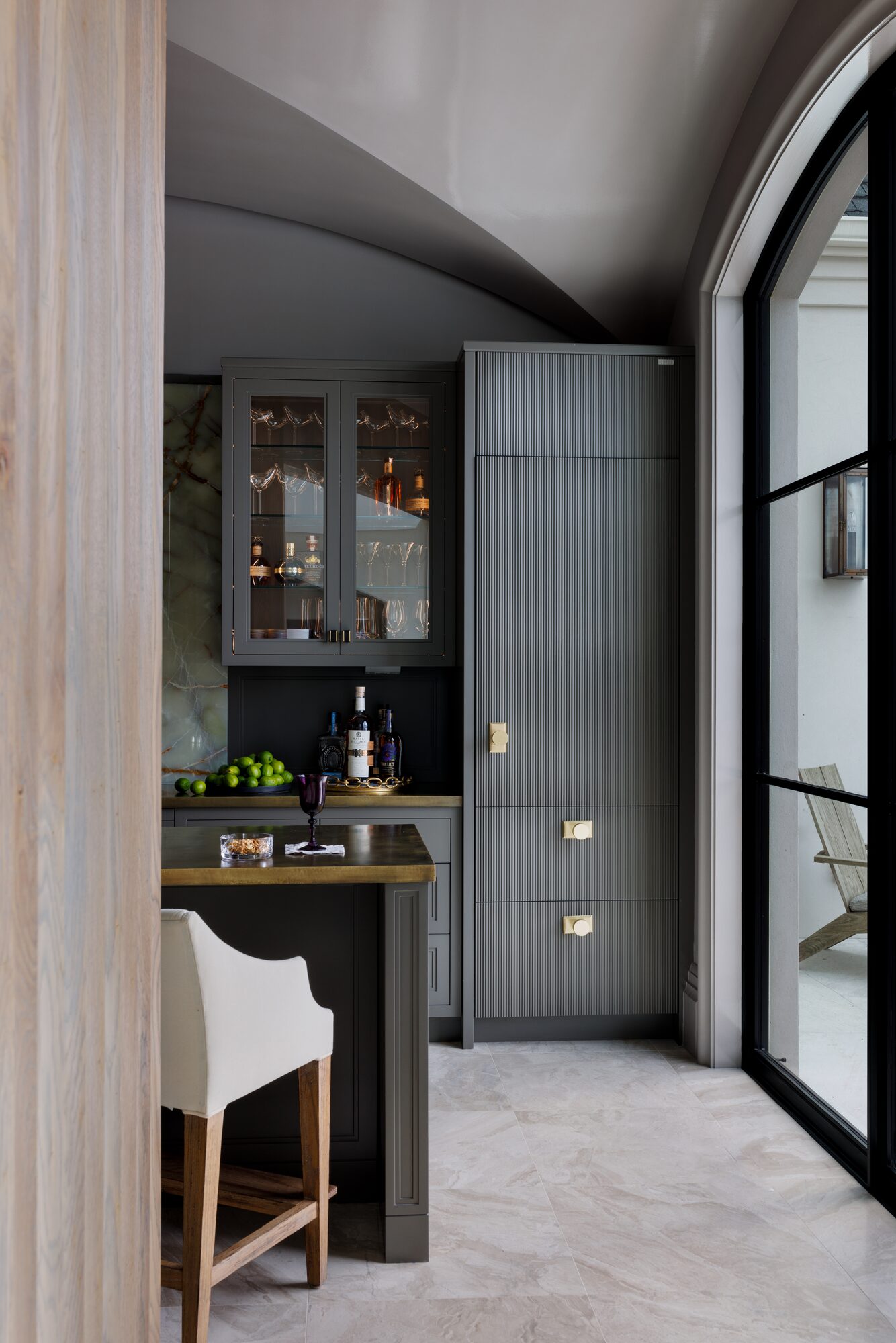 Custom kitchen bar with fluted cabinetry and glass front cabinets