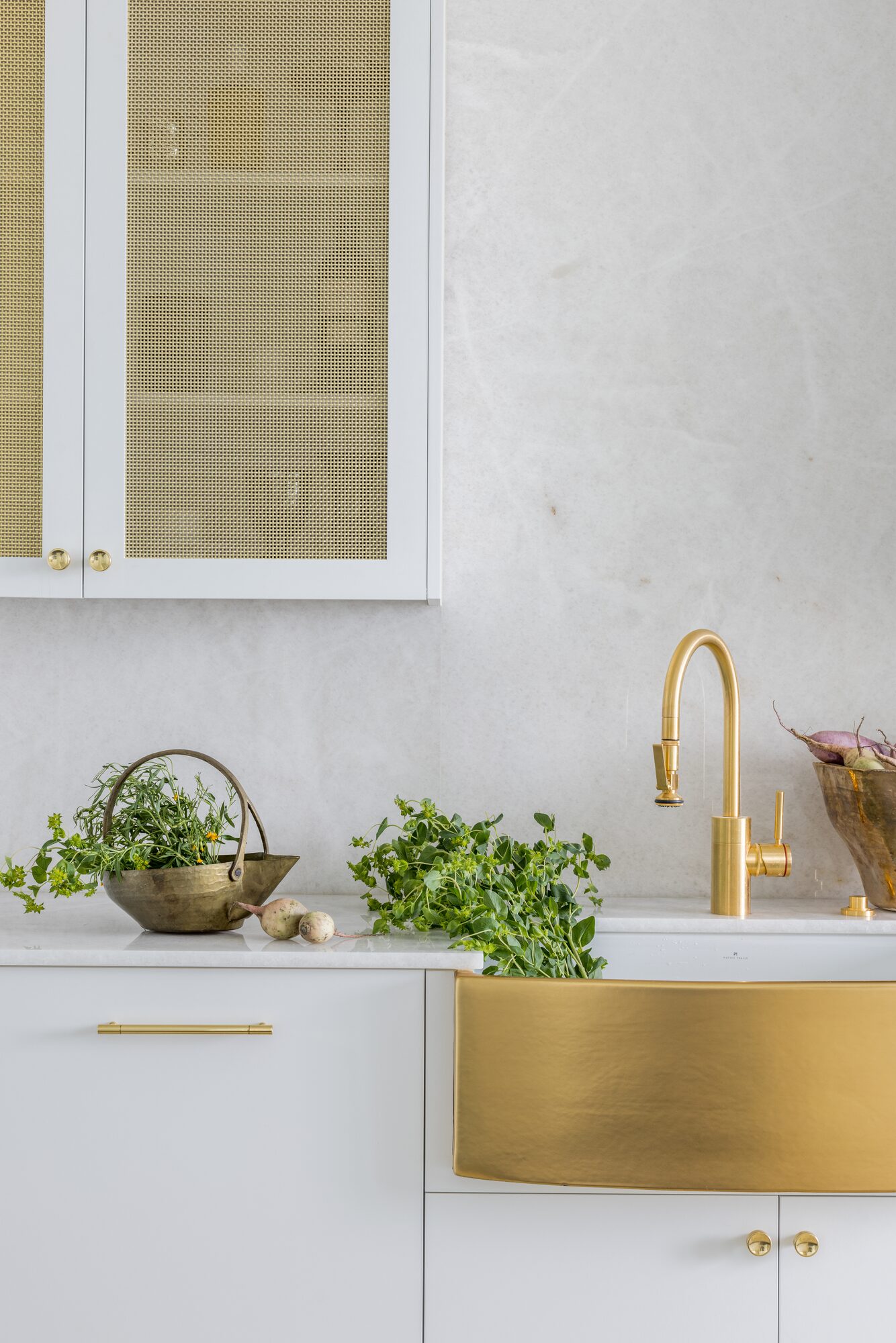 Custom kitchen detail with brass apron sink and white cabinetry