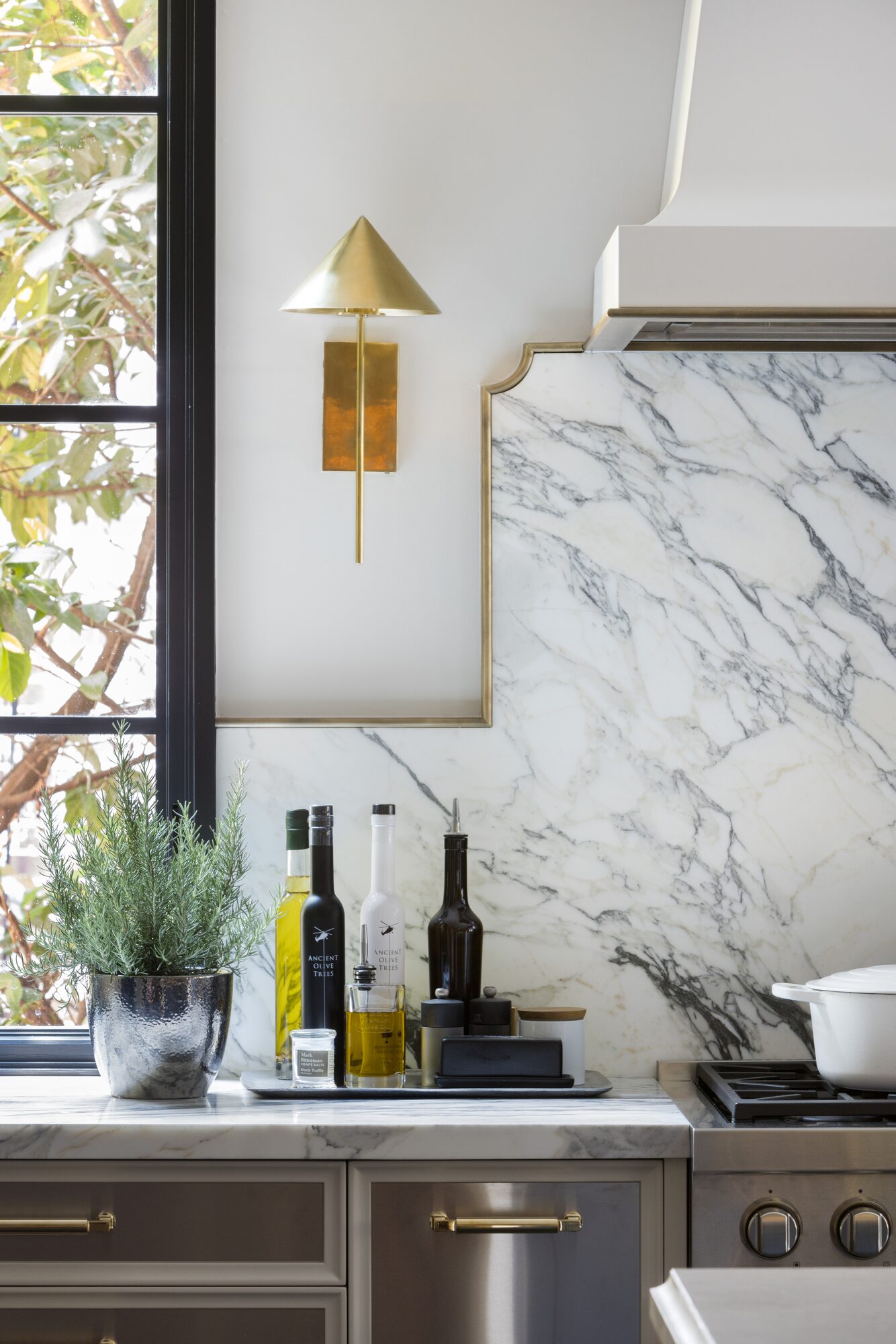 Kitchen with marble backsplash, brass sconce, and styled countertop