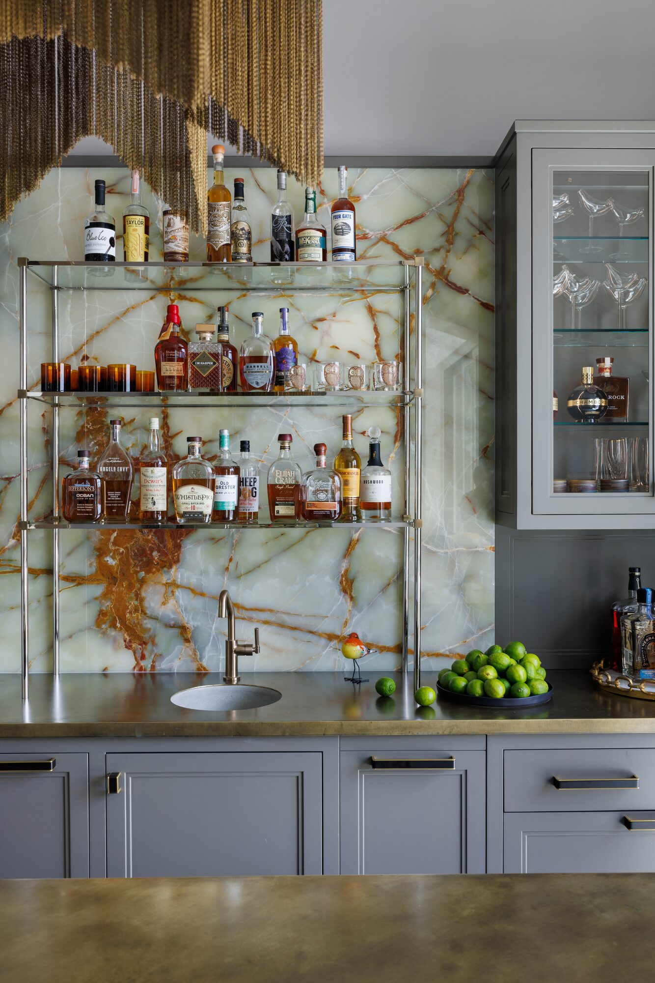 Custom home bar with onyx stone backsplash and brass chain detail — luxury interior photography