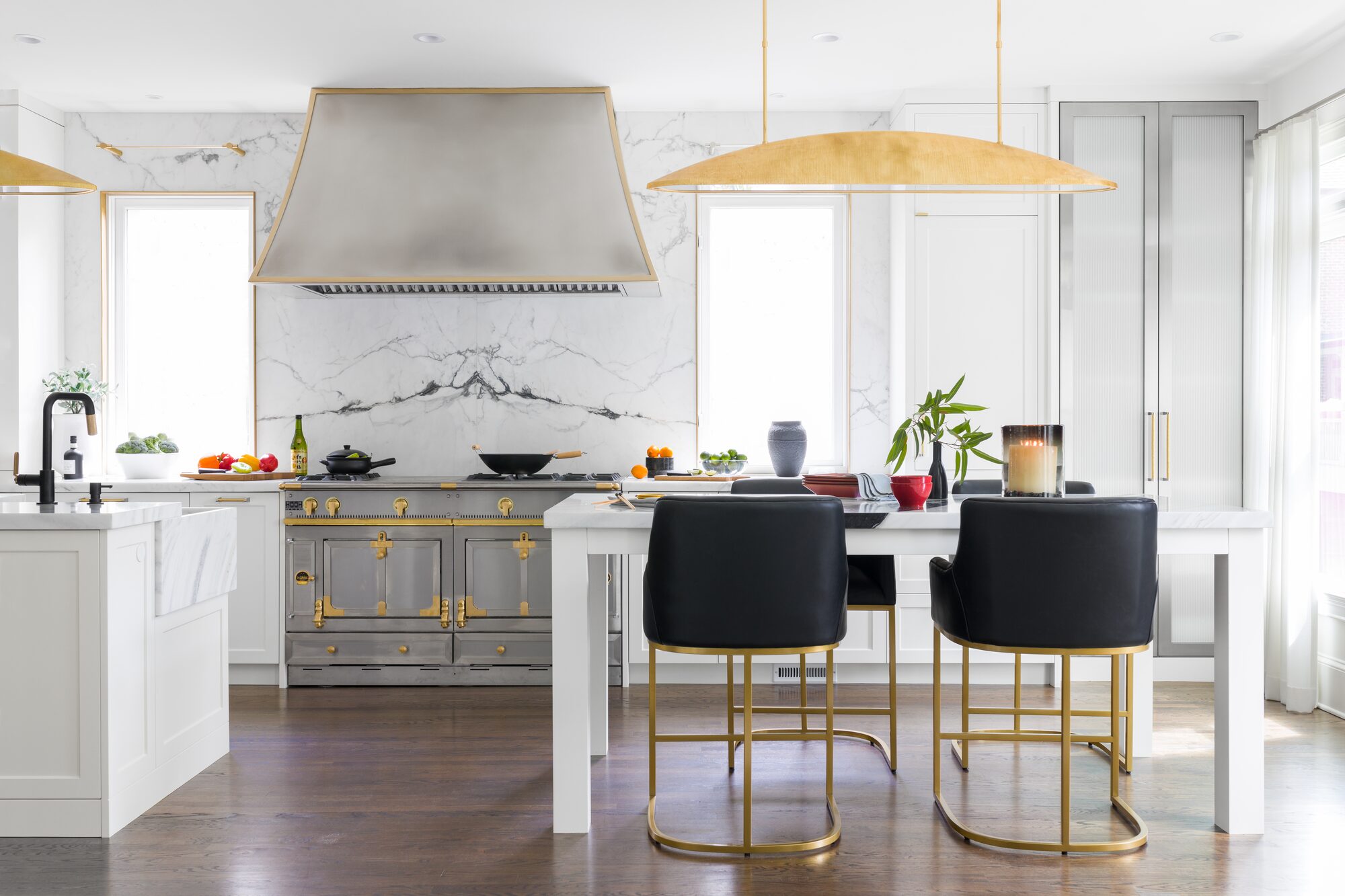 Luxury kitchen with French range, marble backsplash, and brass pendant lighting — interior design photography by Tomas Espinoza