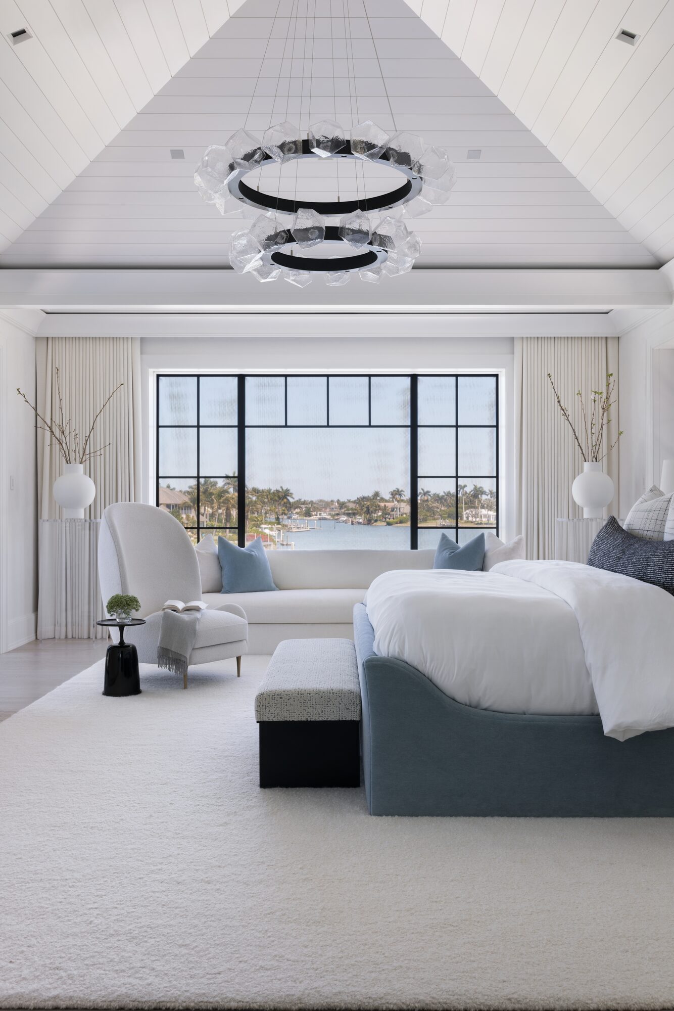 Primary bedroom with vaulted ceiling and waterfront view — residential interior photography