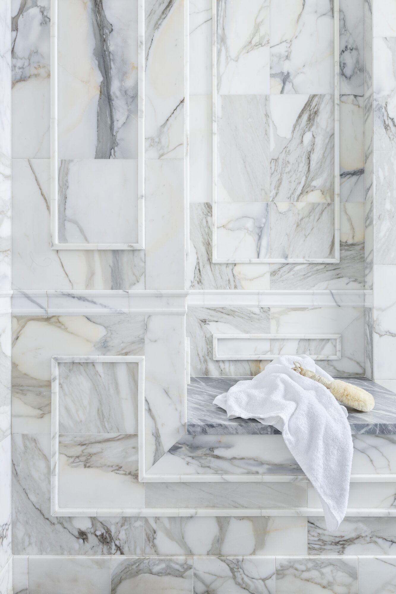 Marble shower wall with integrated niches and stone bench