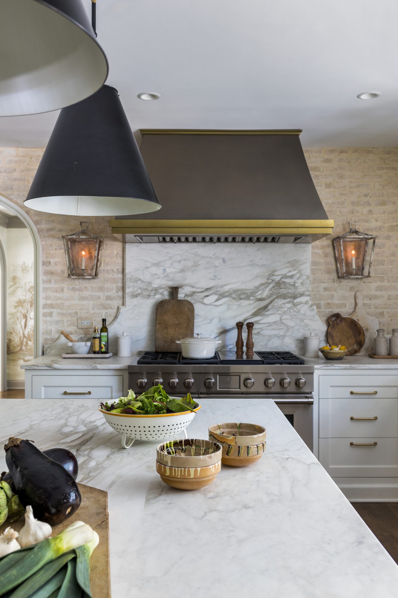Residential kitchen with marble island and brass range hood