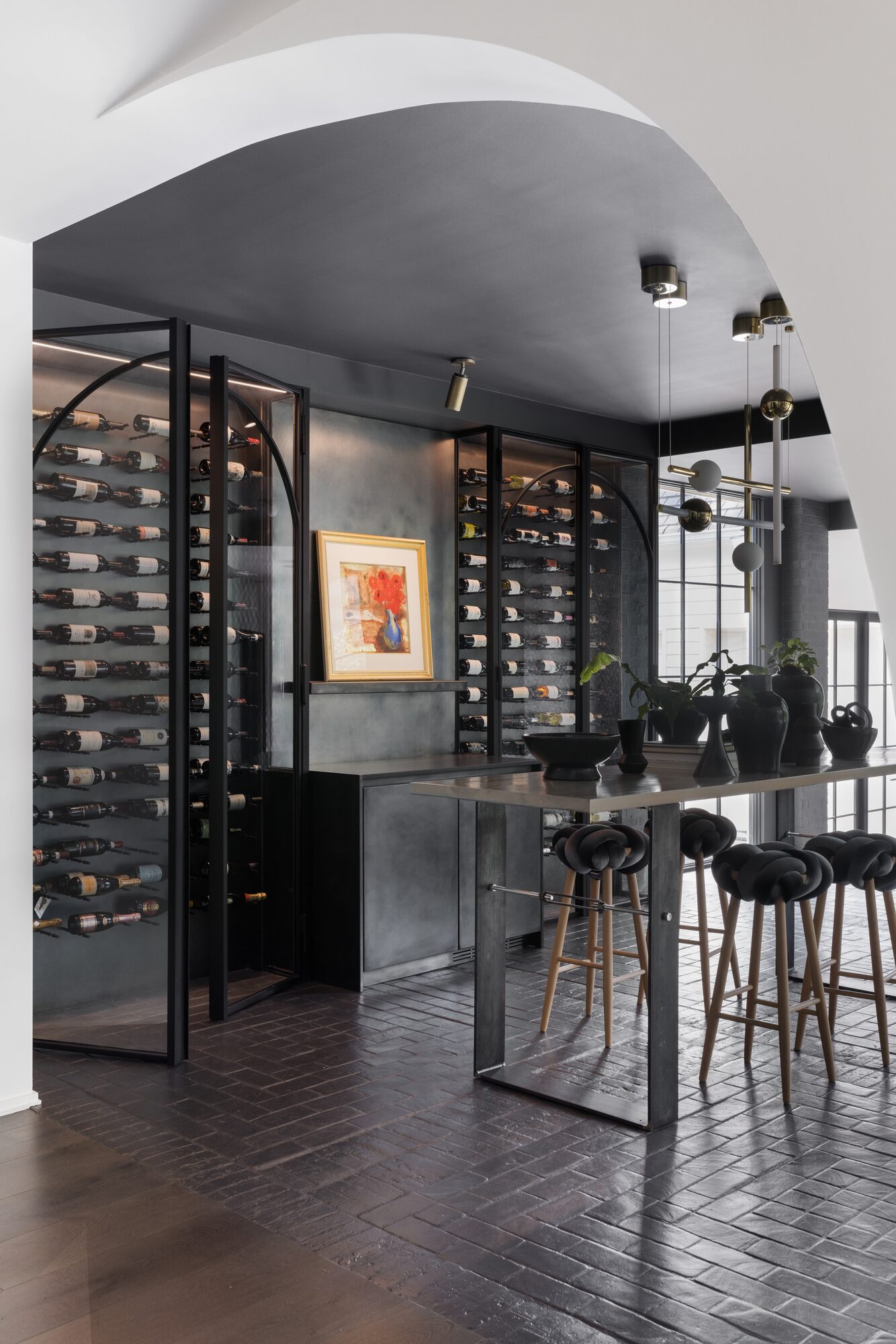 Residential wine cellar with iron and glass doors and herringbone floor